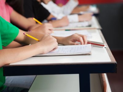 High School Students Writing On Paper At Desk